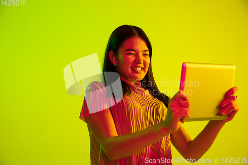 Image of Beautiful girl\'s facial expression in neon light on yellow studio background