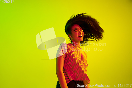 Image of Beautiful girl\'s facial expression in neon light on yellow studio background