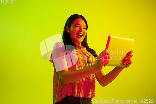 Image of Beautiful girl\'s facial expression in neon light on yellow studio background