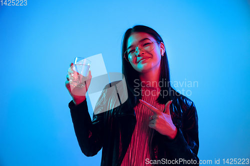 Image of Beautiful girl\'s facial expression in neon light on blue studio background