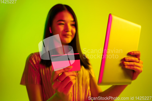 Image of Beautiful girl\'s facial expression in neon light on yellow studio background