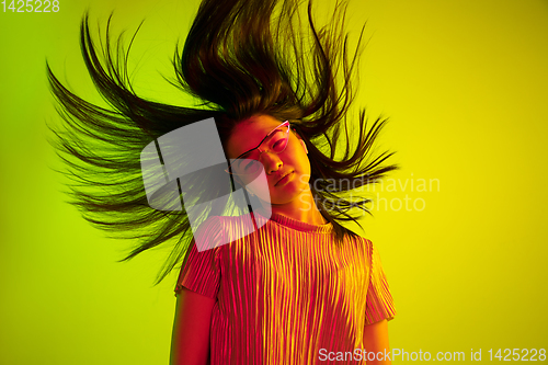 Image of Beautiful girl\'s facial expression in neon light on yellow studio background