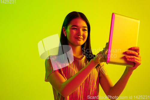 Image of Beautiful girl\'s facial expression in neon light on yellow studio background