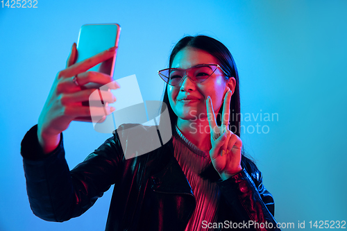 Image of Beautiful girl\'s facial expression in neon light on blue studio background