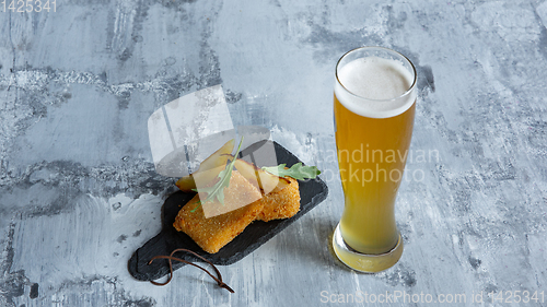 Image of Glass of light beer on white stone background