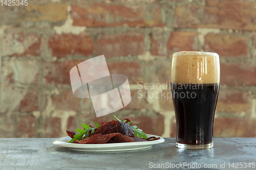 Image of Glass of dark beer on the stone table and brick\'s background
