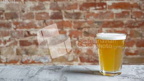 Image of Glass of light beer on white stone background