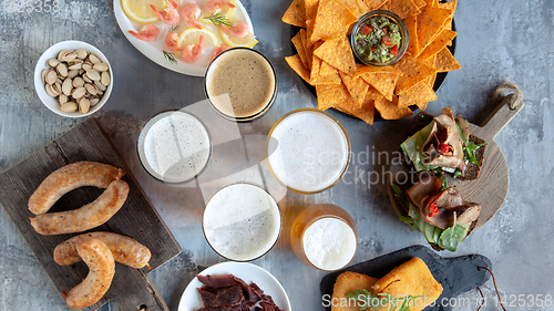Image of Top view of beer glasses with foam on top and delicious snacks