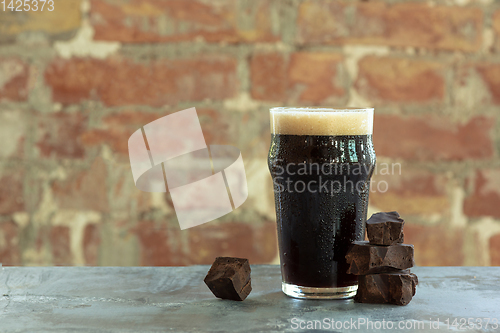 Image of Glass of dark beer on the stone table and brick\'s background