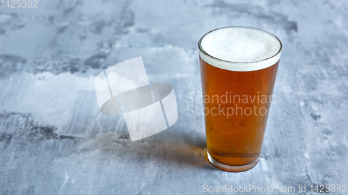 Image of Glass of light beer on white stone background