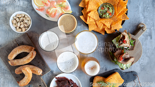 Image of Top view of beer glasses with foam on top and delicious snacks