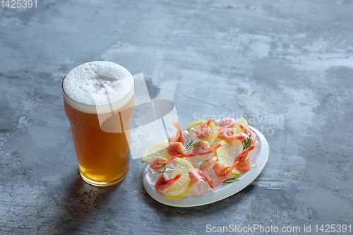 Image of Glass of light beer on white stone background