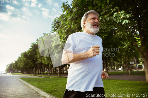 Image of Senior man as runner with armband or fitness tracker at the city\'s street