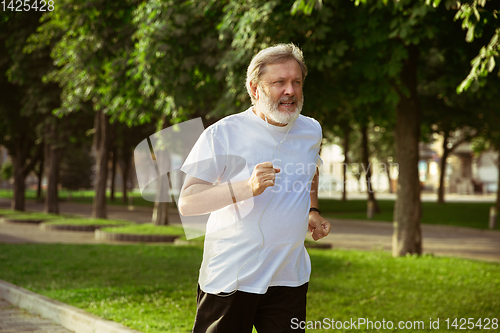 Image of Senior man as runner with armband or fitness tracker at the city\'s street