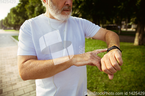 Image of Senior man as runner with armband or fitness tracker at the city\'s street