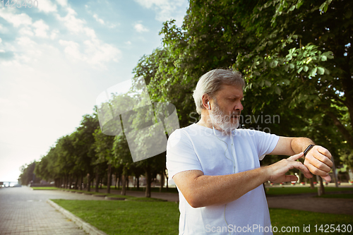 Image of Senior man as runner with armband or fitness tracker at the city\'s street