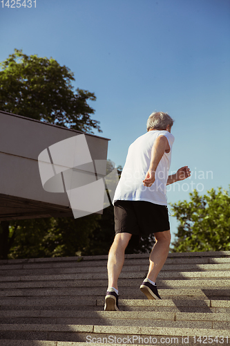 Image of Senior man as runner with armband or fitness tracker at the city\'s street