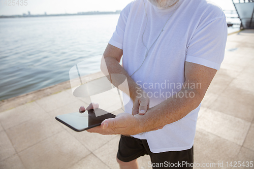 Image of Senior man as runner with armband or fitness tracker at the riverside