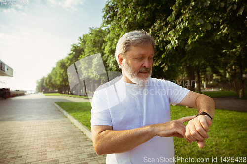 Image of Senior man as runner with armband or fitness tracker at the city\'s street