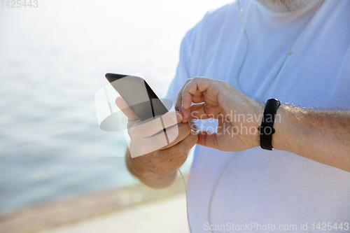 Image of Senior man as runner with armband or fitness tracker at the riverside