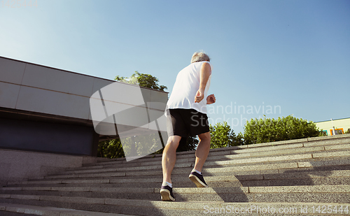 Image of Senior man as runner with armband or fitness tracker at the city\'s street