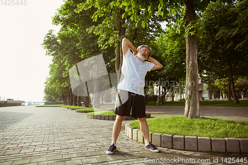 Image of Senior man as runner with armband or fitness tracker at the city\'s street