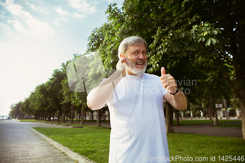 Image of Senior man as runner with armband or fitness tracker at the city\'s street