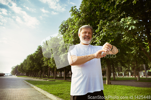 Image of Senior man as runner with armband or fitness tracker at the city\'s street