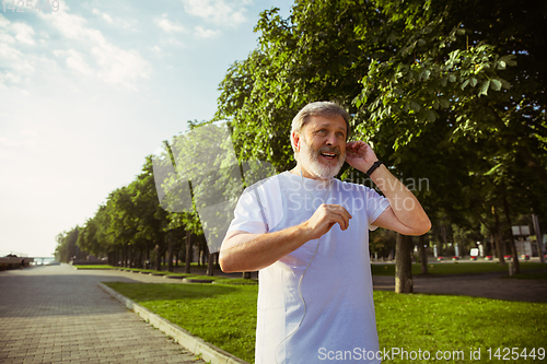 Image of Senior man as runner with armband or fitness tracker at the city\'s street