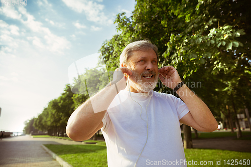 Image of Senior man as runner with armband or fitness tracker at the city\'s street