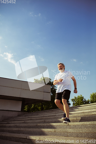 Image of Senior man as runner with armband or fitness tracker at the city\'s street