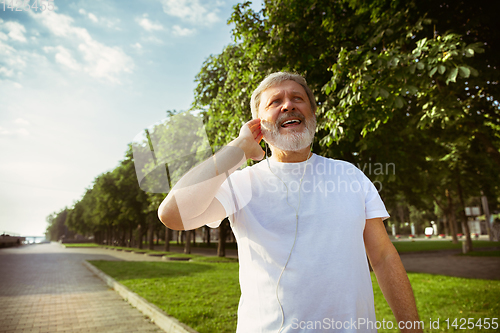 Image of Senior man as runner with armband or fitness tracker at the city\'s street