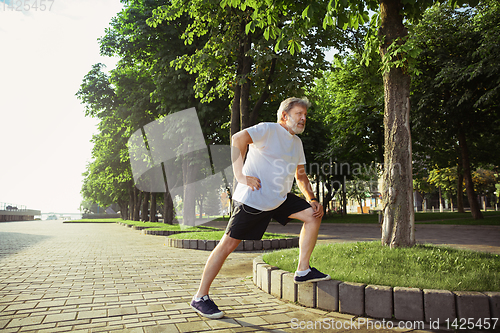 Image of Senior man as runner with armband or fitness tracker at the city\'s street