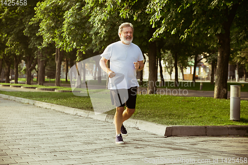 Image of Senior man as runner with armband or fitness tracker at the city\'s street