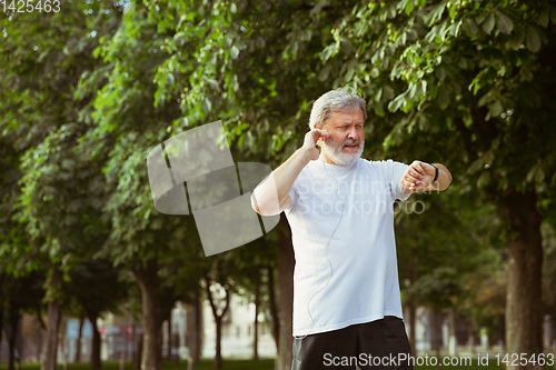 Image of Senior man as runner with armband or fitness tracker at the city\'s street