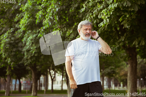 Image of Senior man as runner with armband or fitness tracker at the city\'s street