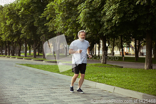 Image of Senior man as runner with armband or fitness tracker at the city\'s street