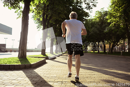 Image of Senior man as runner with armband or fitness tracker at the city\'s street