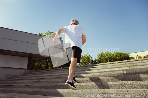 Image of Senior man as runner with armband or fitness tracker at the city\'s street