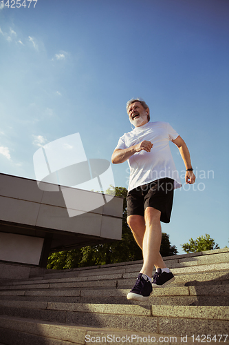 Image of Senior man as runner with armband or fitness tracker at the city\'s street