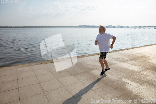 Image of Senior man as runner with armband or fitness tracker at the riverside