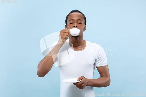 Image of Half-length close up portrait of young man on blue background.