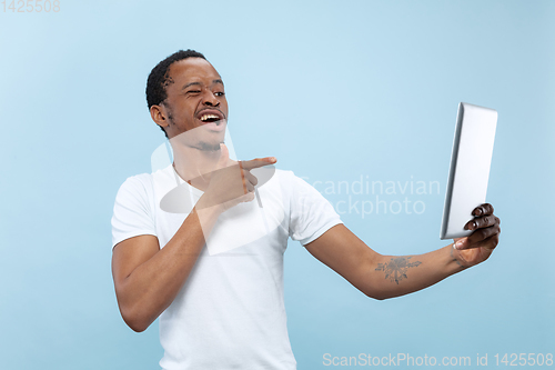 Image of Half-length close up portrait of young man on blue background.