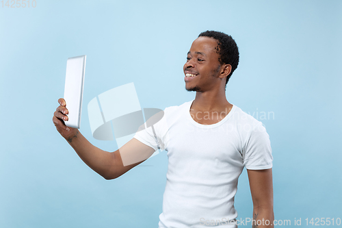 Image of Half-length close up portrait of young man on blue background.