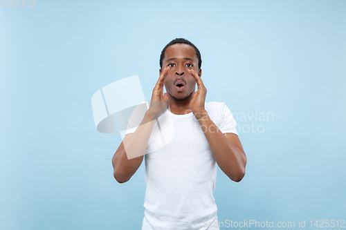 Image of Half-length close up portrait of young man on blue background.