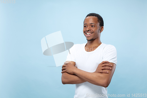 Image of Half-length close up portrait of young man on blue background.