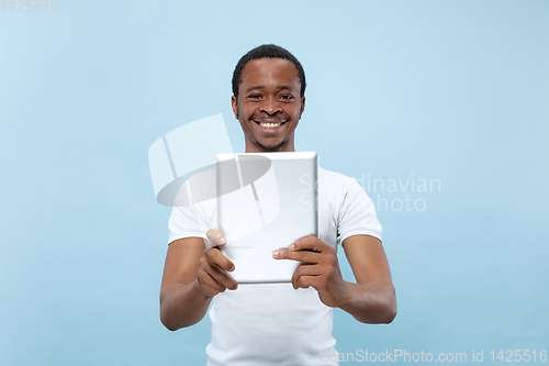 Image of Half-length close up portrait of young man on blue background.