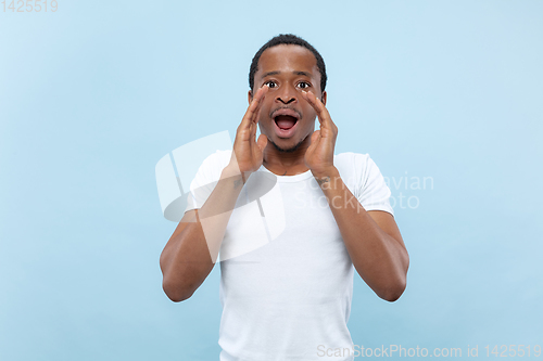 Image of Half-length close up portrait of young man on blue background.