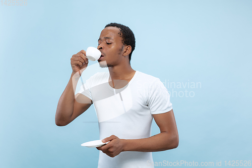 Image of Half-length close up portrait of young man on blue background.