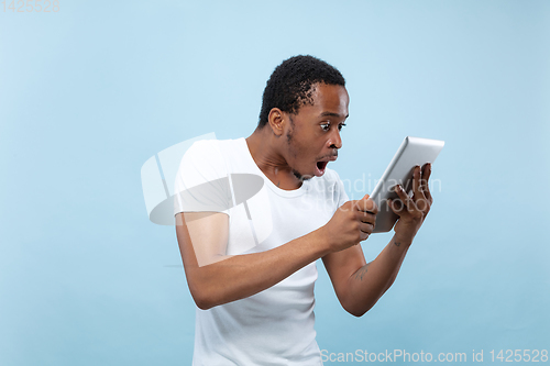 Image of Half-length close up portrait of young man on blue background.